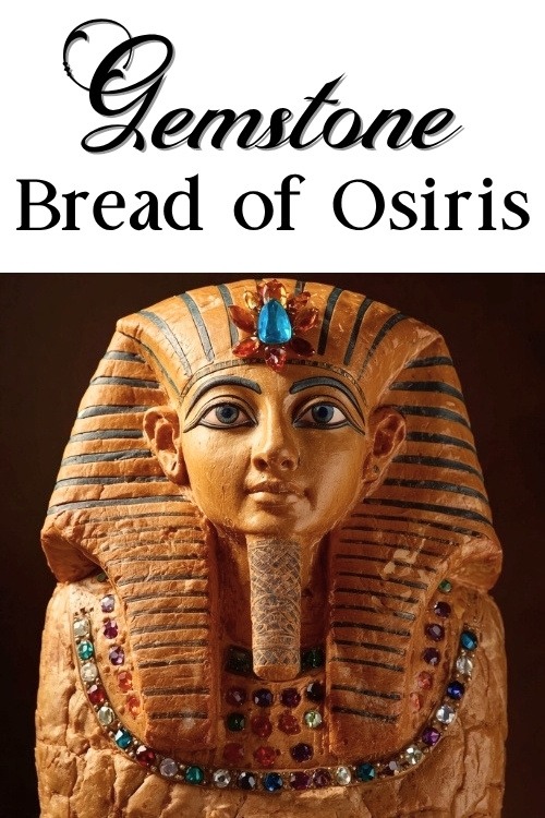 A loaf of bread in the style of an Ancient Egyptian pharaohs mask with detailed blue and gold striped headdress, adorned with colourful gemstones. Text reads gemstone bread of osiris