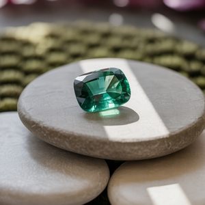 A radiant green emerald gemstone sits atop smooth, stacked stones, bathed in sunlight. The scene conveys tranquility and natural beauty.