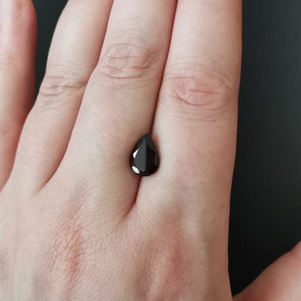 The dark red garnet gem resting on a hand to give an idea of the gemstone size and colour.