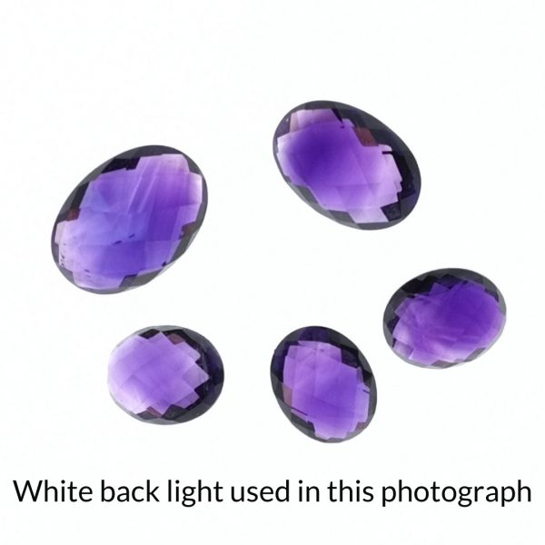 The purple amethyst oval gems is being back-lit with a bright white light to show any inclusions within the gems more clearly.