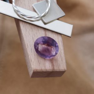 The purple amethyst oval displayed on a jewellers bench peg with some sterling silver sheet and wire.