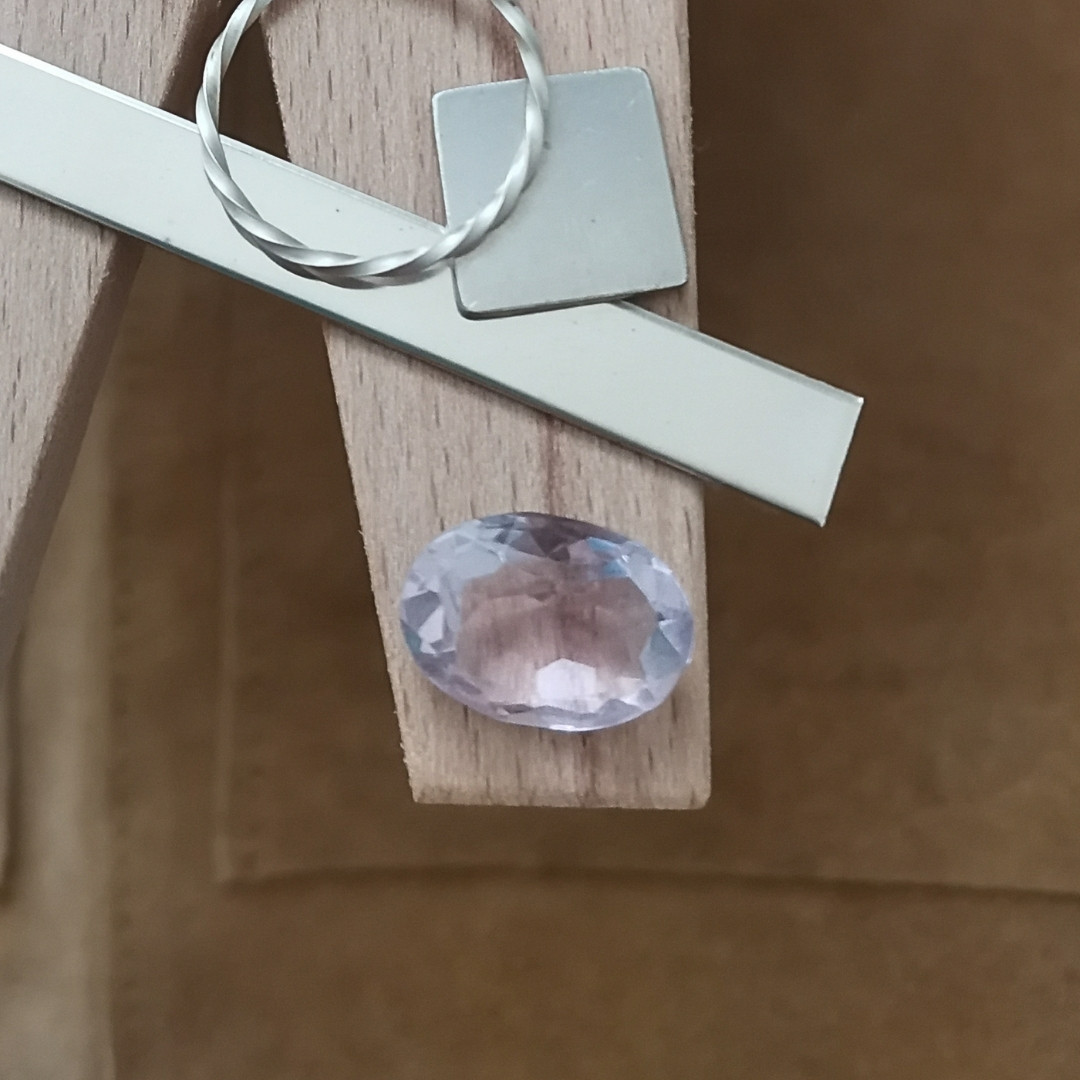 The lavender amethyst oval displayed on a jewellers bench peg with some sterling silver sheet and wire.