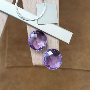 The purple amethyst rounds displayed on a jewellers bench peg with some sterling silver sheet and wire.