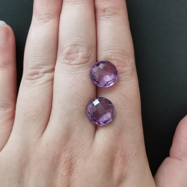 The purple amethyst gemstones resting on a hand to give an idea of the gemstone size and colour.