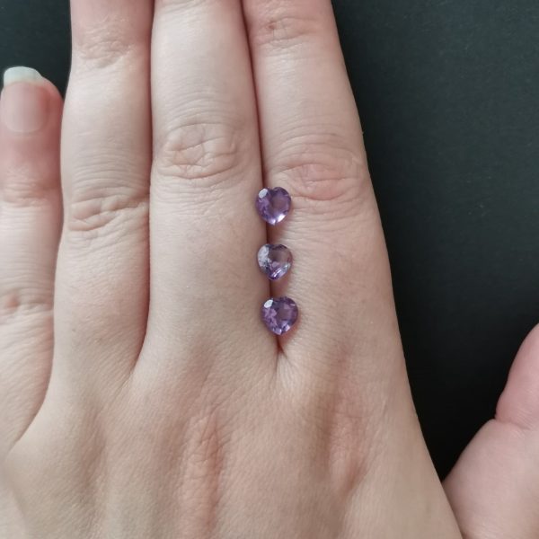 The purple amethyst gemstones resting on a hand to give an idea of the gemstone size and colour.