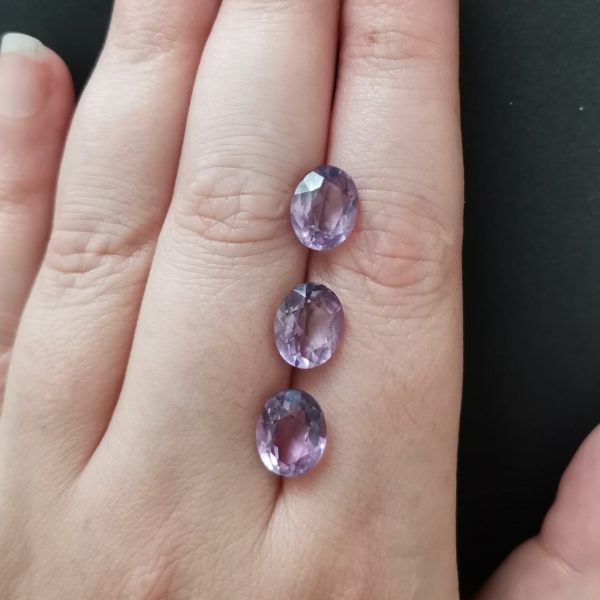 The purple amethyst gemstones resting on a hand to give an idea of the gemstone size and colour.