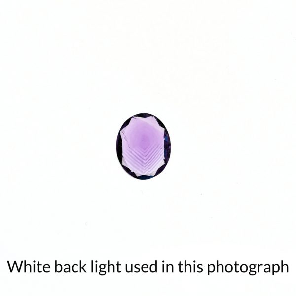 The purple amethyst oval gem is being back-lit with a bright white light to show any inclusions within the gem more clearly.