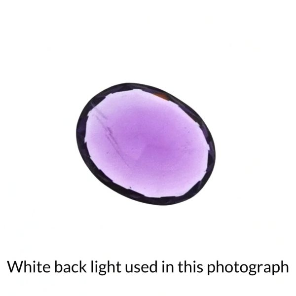 The purple amethyst oval gem is being back-lit with a bright white light to show any inclusions within the gem more clearly.