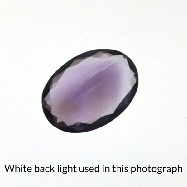 The purple amethyst oval gem is being back-lit with a bright white light to show any inclusions within the gem more clearly.