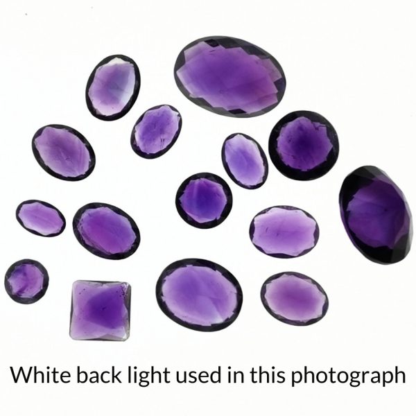 The bundle of purple amethyst gems are being back-lit with a bright white light to show any inclusions within the gem more clearly.