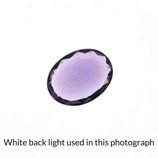 The purple amethyst oval gem is being back-lit with a bright white light to show any inclusions within the gem more clearly.