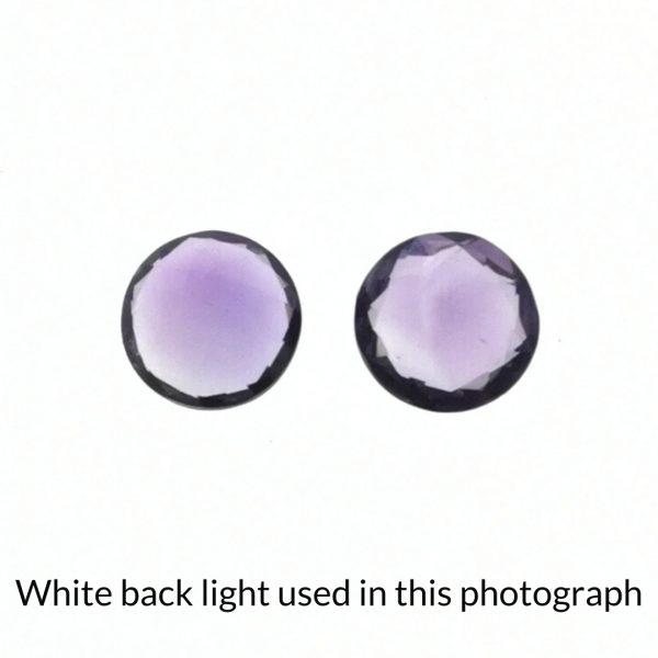 The purple amethyst round gems are being back-lit with a bright white light to show any inclusions within the gems more clearly.