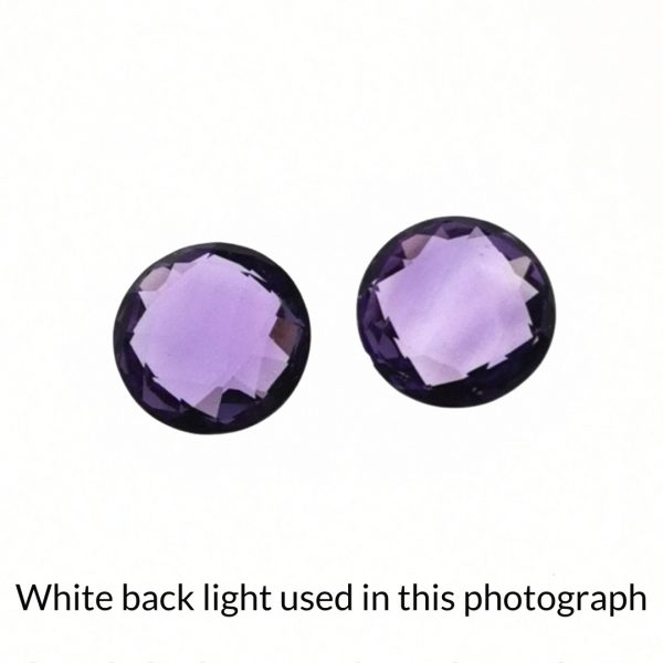 The purple amethyst round gems are being back-lit with a bright white light to show any inclusions within the gems more clearly.
