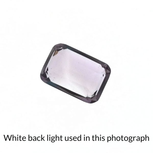 The purple amethyst rectangle gem is being back-lit with a bright white light to show any inclusions within the gem more clearly.