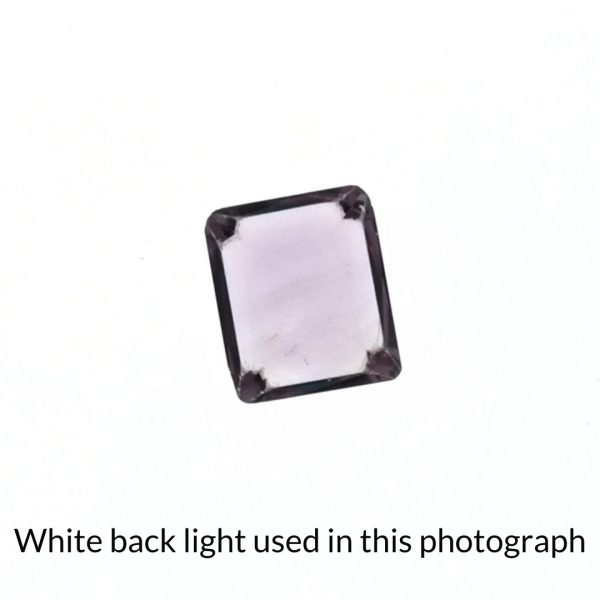 The purple amethyst rectangle gem is being back-lit with a bright white light to show any inclusions within the gem more clearly.