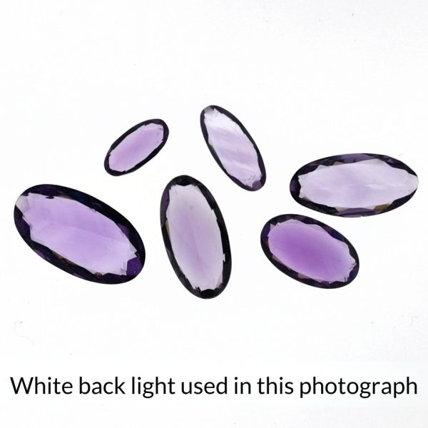 The purple amethyst oval gems is being back-lit with a bright white light to show any inclusions within the gem more clearly.