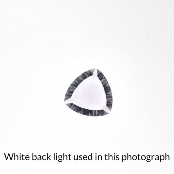 The purple amethyst oval gem is being back-lit with a bright white light to show any inclusions within the gem more clearly.