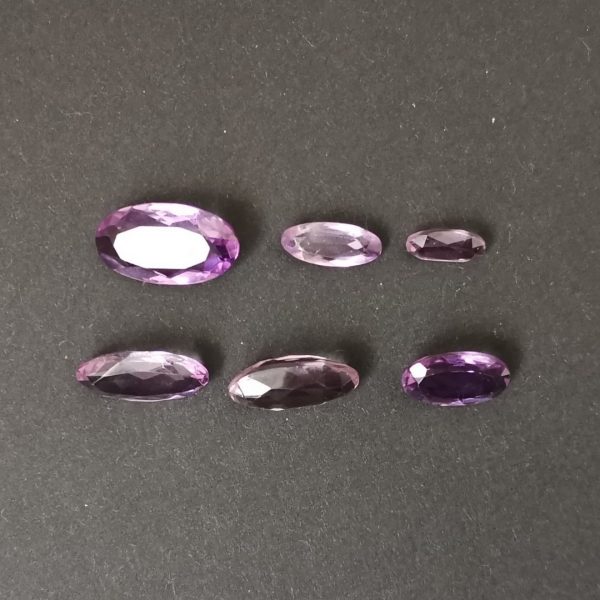 the 6 elongated oval amethyst gemstones displayed on a black background