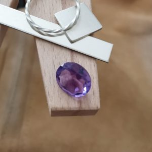 The purple amethyst oval displayed on a jewellers bench peg with some sterling silver sheet and wire.