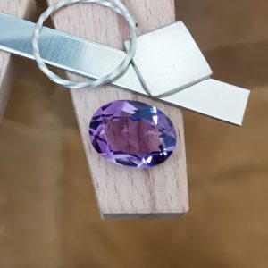 The purple amethyst oval displayed on a jewellers bench peg with some sterling silver sheet and wire.