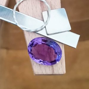 The purple amethyst oval displayed on a jewellers bench peg with some sterling silver sheet and wire.