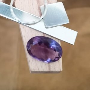 The purple amethyst oval displayed on a jewellers bench peg with some sterling silver sheet and wire.