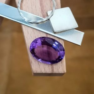 The purple amethyst oval displayed on a jewellers bench peg with some sterling silver sheet and wire.
