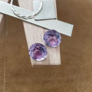 The pair of purple amethyst rounds displayed on a jewellers bench peg with some sterling silver sheet and wire.