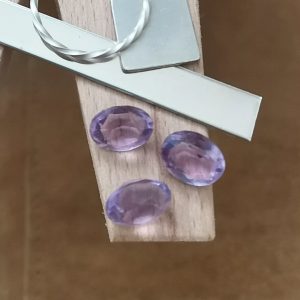 The purple amethyst ovals displayed on a jewellers bench peg with some sterling silver sheet and wire.