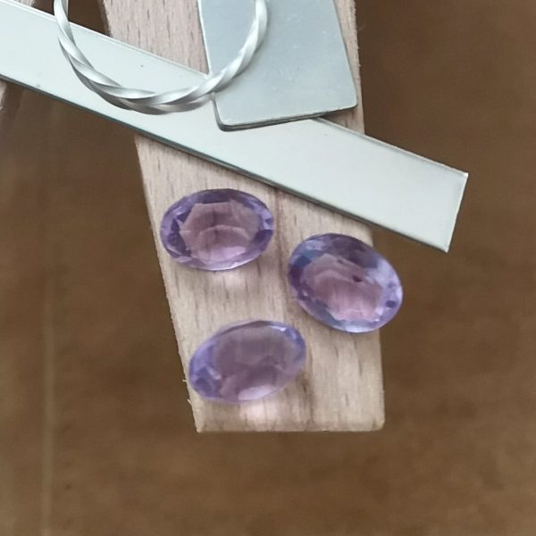 The purple amethyst ovals displayed on a jewellers bench peg with some sterling silver sheet and wire.