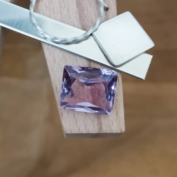 The purple amethyst rectangle displayed on a jewellers bench peg with some sterling silver sheet and wire.