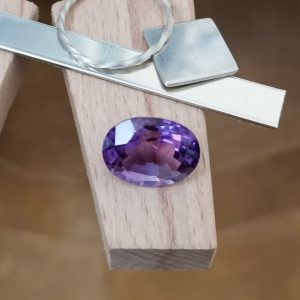 The purple amethyst oval displayed on a jewellers bench peg with some sterling silver sheet and wire.