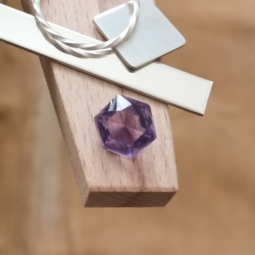 The purple amethyst hexagon displayed on a jewellers bench peg with some sterling silver sheet and wire.