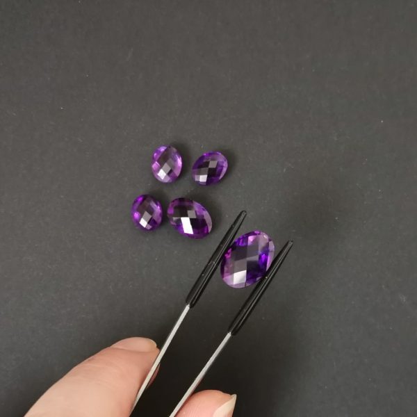 A photo of the checkerboard cut crown area of the purple amethysts against a black background