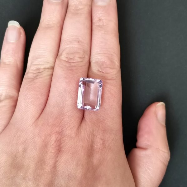 The purple amethyst gemstone resting on a hand to give an idea of the gemstones size and colour.