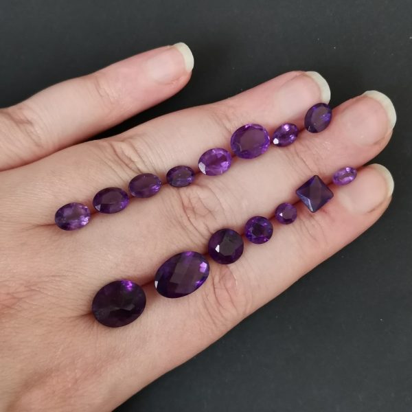 The purple amethyst gemstones resting on a hand to give an idea of the gemstones size and colour.