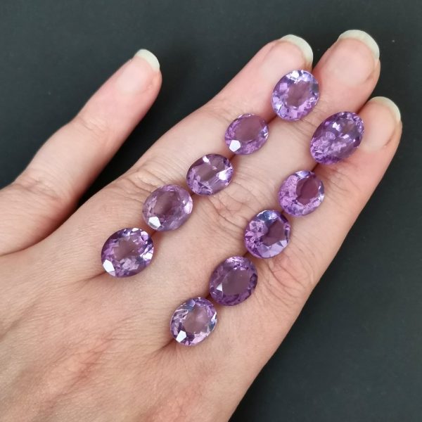 The purple amethyst gemstones resting on a hand to give an idea of the gemstones size and colour.