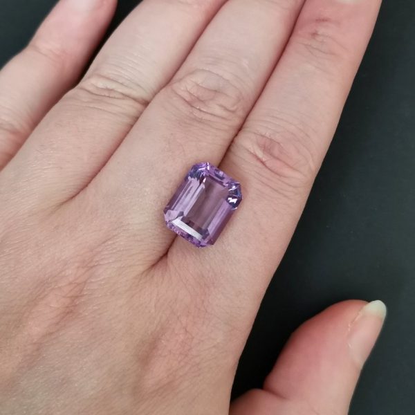 The purple amethyst gemstone resting on a hand to give an idea of the gemstones size and colour.