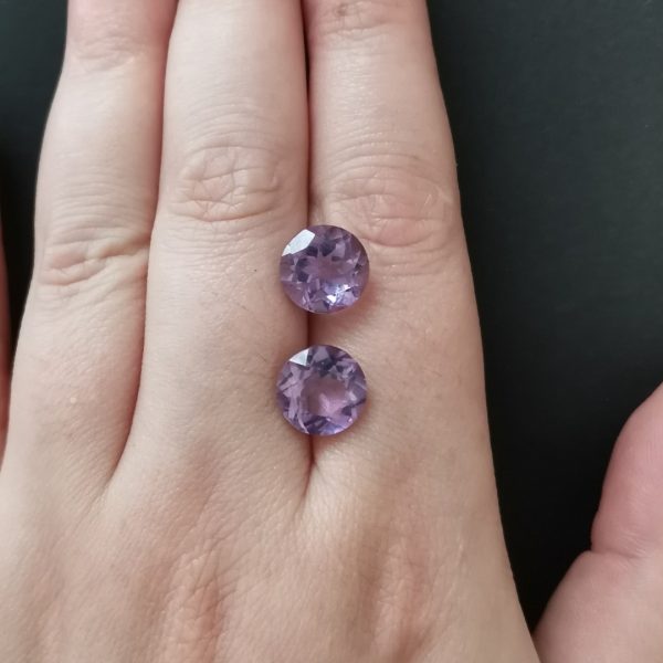 The purple amethyst gemstones resting on a hand to give an idea of the gemstone size and colour.