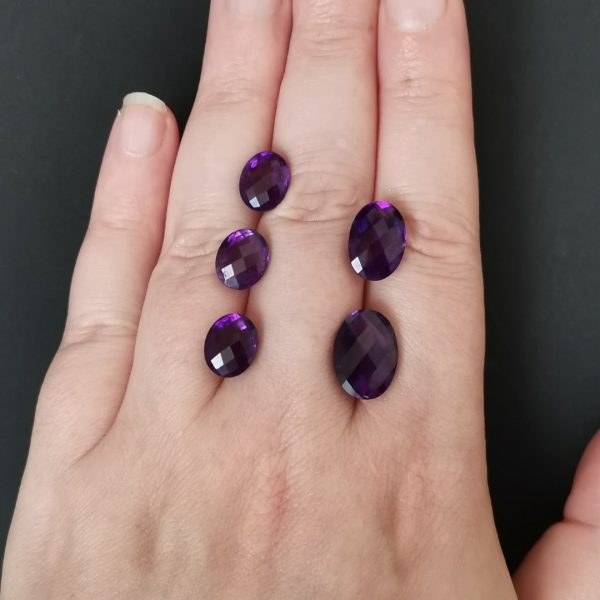 The purple amethyst gemstones resting on a hand to give an idea of the gemstones size and colour.