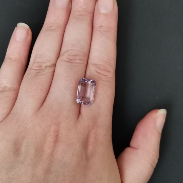 The purple amethyst gemstone resting on a hand to give an idea of the gemstone size and colour.