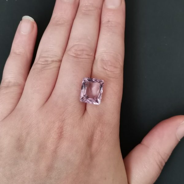 The purple amethyst gemstone resting on a hand to give an idea of the gemstone size and colour.