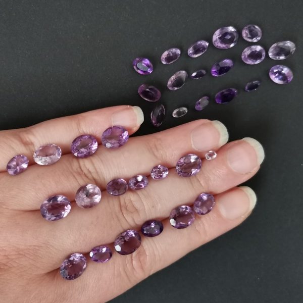The purple amethyst gemstones resting on a hand to give an idea of the gemstones size and colour.