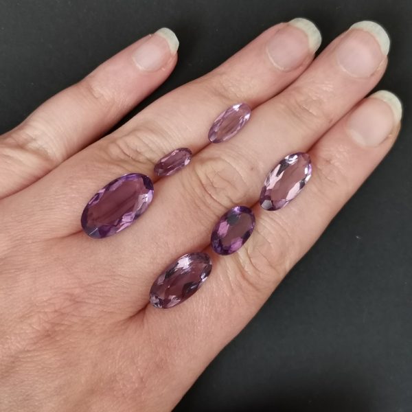 The purple amethyst gemstones resting on a hand to give an idea of the gemstones size and colour.