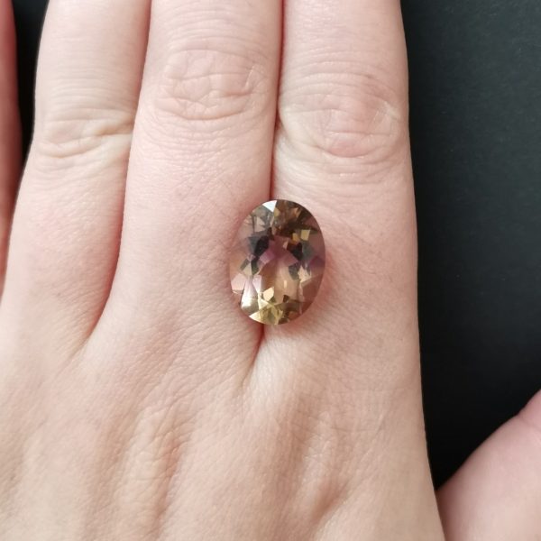 The purple and yellow ametrine gemstone resting on a hand to give an idea of the gemstone size and colour.