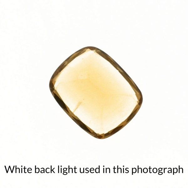 The orange citrine cushion gem is being back-lit with a bright white light to show any inclusions within the gem more clearly.