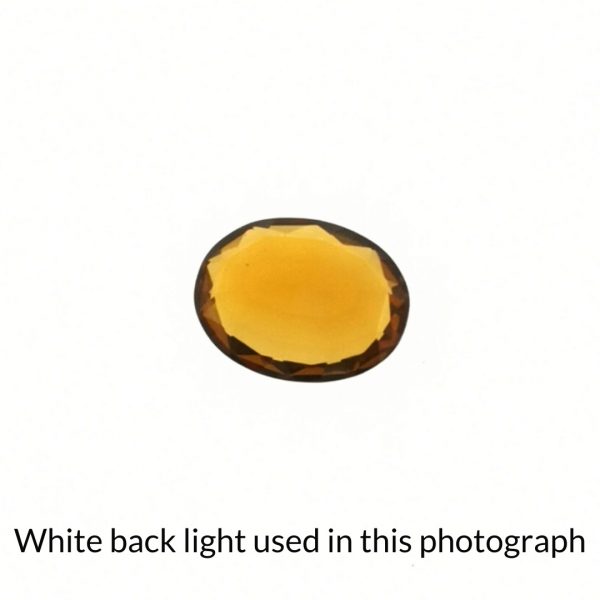 The orange citrine oval gem is being back-lit with a bright white light to show any inclusions within the gem more clearly.