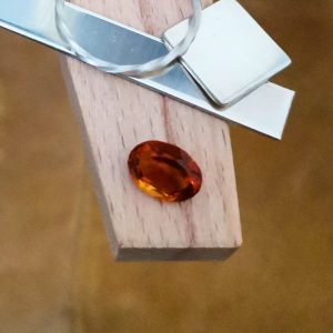 The orange citrine oval displayed on a jewellers bench peg with some sterling silver sheet and wire.