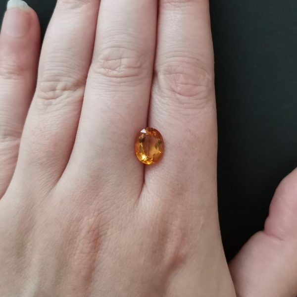 The orange citrine gemstone resting on a hand to give an idea of the gemstone size and colour.