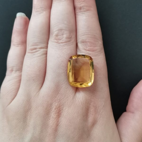 The orange citrine gemstone resting on a hand to give an idea of the gemstone size and colour.